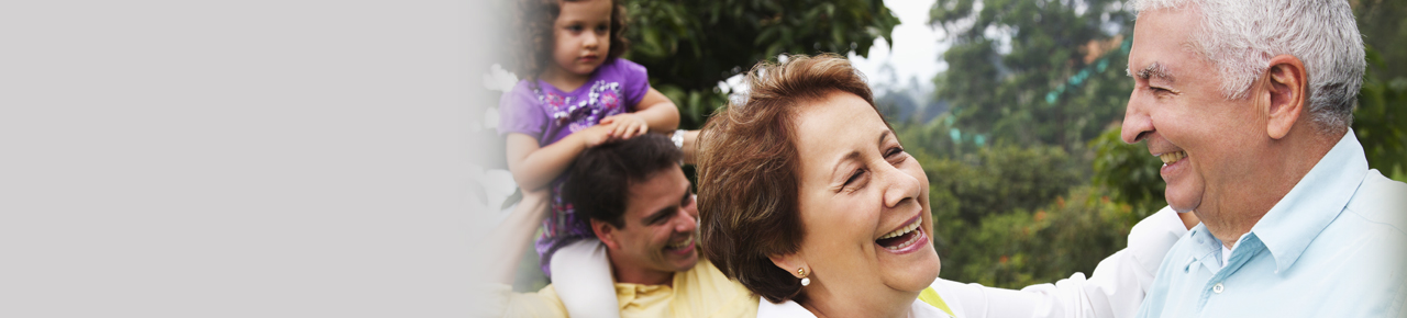 Retired couple laughing and smiling at each other with their adult son and granddaughter in the background