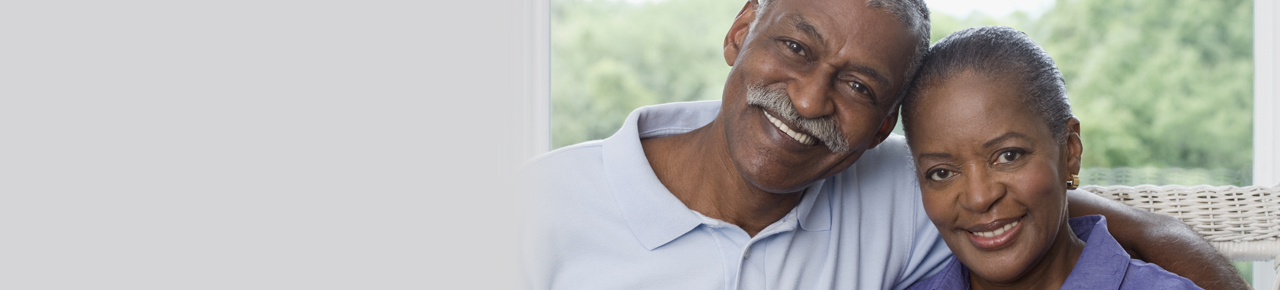 Older couple with man's arm around his wife as both smile