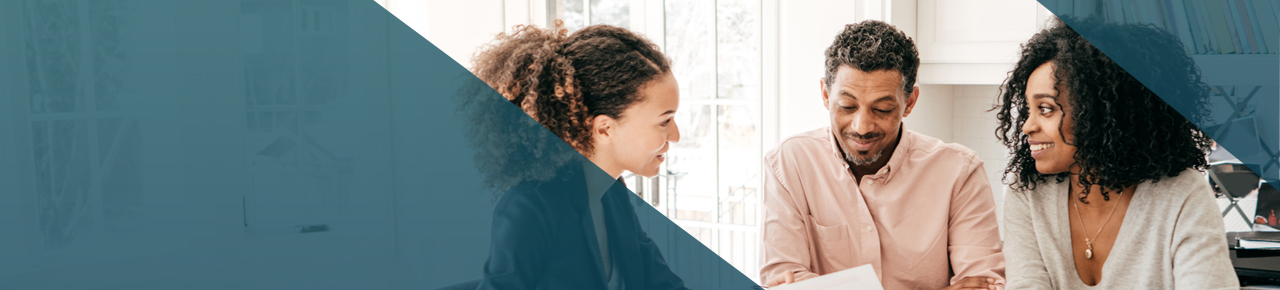 40-something couple sitting with a woman advisor smiling and talking